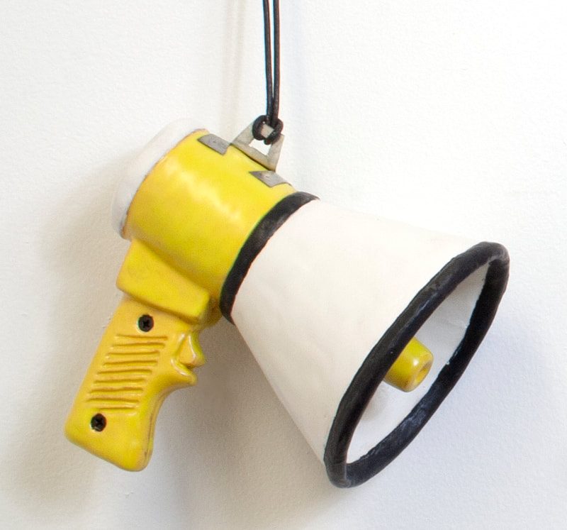 clay sculpture of a Megaphone hanging on a wall. 