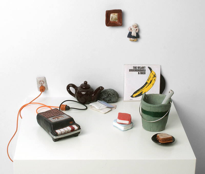 small clay objects on a white shelf. including a record, tape recorder, teapot and bucket. 