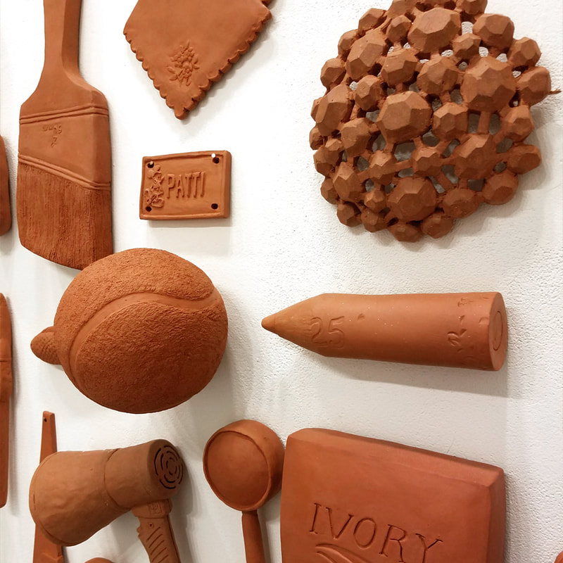 Terra cotta objects on a white wall. 
