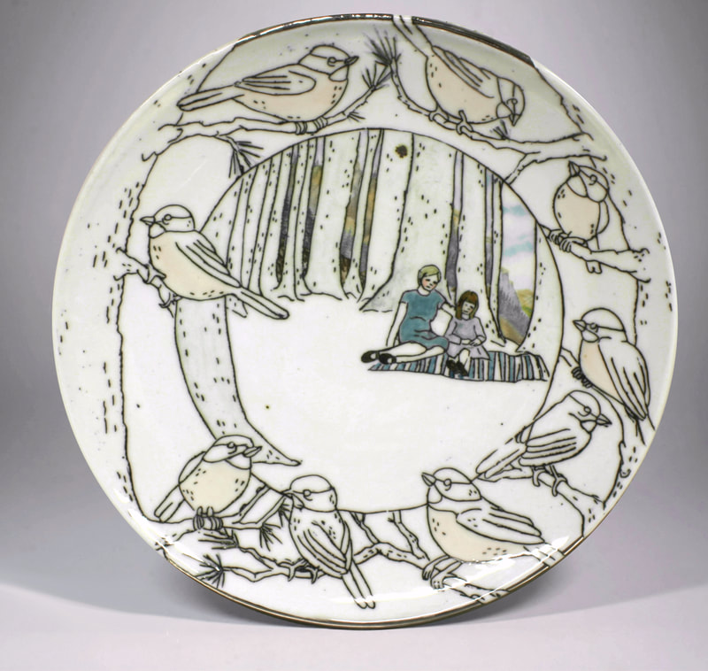 porcelain plate with inlaid drawing of mother and child on a blanket surrounded by birds